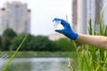 A gloved hand holds a beaker with a sample of water. Sampling from open water. Scientist or biologist takes a water