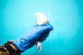 Gloved hand holds medical mask over blue background.