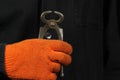 A gloved hand holds a pair of pliers on a black background close up