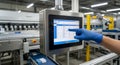 Gloved hand interacting with industrial touchscreen display in modern automated manufacturing facility Royalty Free Stock Photo