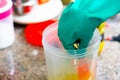 Gloved hand mixing oil with lye solution for saponification in plastic container Royalty Free Stock Photo