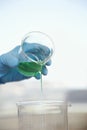 Gloved Hand Pouring Green Liquid Into Beaker