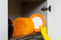 a gloved hand puts a washed plate in the drying cupboard.