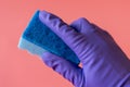 Gloved hand with washcloth on pink background. Rubber gloves and a washcloth for cleaning on a pink background. Set of rubber