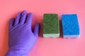 Gloved hand with washcloth on pink background. Rubber gloves and a washcloth for cleaning on a pink background. Set of rubber