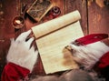Gloved hands of Father Christmas writing on a blank vintage parchment scroll with copy space with a feather quill by the light of