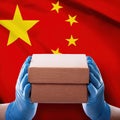 Hands holding a brown box in front of the Chinese flag with red and yellow colors Royalty Free Stock Photo