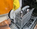 Gloved hands loading or emptying dishwasher closeup