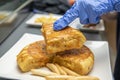 Gloved hands separating a piece of tortilla to make a Spanish tapa with country peaks