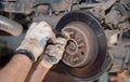 Gloved hands unscrew the rear rusted wheel hub with a screwdriver. Royalty Free Stock Photo