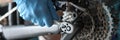Gloved handyman fixing bicycle chain with tools closeup