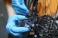 Gloved handyman repairs rear cassette of bicycle