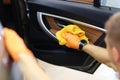 Gloved handyman wipes car doors inside cabin closeup