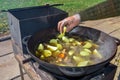 A gloved man`s hand throws potatoes into the broth. Boil the broth with meat and vegetables in a cauldron. Cooking Royalty Free Stock Photo