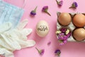 Gloves, facemask, flowers and eggs with inscription EASTER over pink background Royalty Free Stock Photo