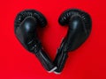 The gloves are off now. High angle shot of a pair of boxing gloves placed together on top of a red background inside of