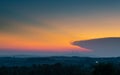 Glow in sky around big cloud at twilight above hilly rural landscape in haze Royalty Free Stock Photo