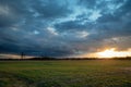 The glow of the sun coming out from behind a dark cloud over a green meadow, evening view Royalty Free Stock Photo