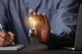 Glow up your ideas. Closeup view of man holding light bulb while working at wooden desk Royalty Free Stock Photo