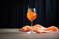 glowing aperol spritz, clear glass against a black cloth