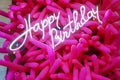 Glowing birthday inscription on the background of pink inflatable balloons.