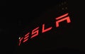 Glowing bright red Tesla logo on a dark night background close-up Royalty Free Stock Photo