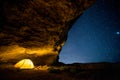 Glowing camping tent in the night grotto under a starry sky