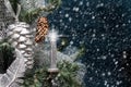 Glowing candle on Christmas tree with pine cone by night on background of falling snow.