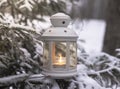 Glowing candle in lantern hanging on fir tree branch in winter forest. Christmas scene Royalty Free Stock Photo