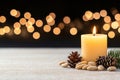 Glowing candle with pine cones and almonds in a festive holiday setting. Concept of light and hope for all. Royalty Free Stock Photo