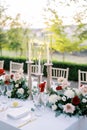 Glowing candles in candlesticks with glass caps stand on a festive table among flowers