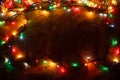 A glowing Christmas garland in the background of burlap in the dark.