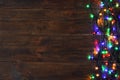 Glowing Christmas lights on brown wooden background, top view Royalty Free Stock Photo