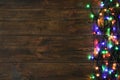 Glowing Christmas lights on brown wooden background, top view. Royalty Free Stock Photo