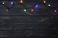 Glowing Christmas lights on dark wooden background Royalty Free Stock Photo