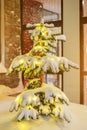 A small Christmas tree glows at night in the snow. Glowing Christmas tree under the snow on the evening street. Glowing Royalty Free Stock Photo