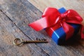 Glowing deep blue with red ribbon gift box and Love key shape on vintage wooden table. A present with love concept. Backdrop for Royalty Free Stock Photo