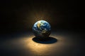 A glowing earth model sits on a dark surface, illuminated by a spotlight from above Royalty Free Stock Photo