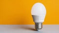 Egg-shaped lightbulb glowing softly against a vibrant yellow background, symbolizing creativity and fresh ideas with ample copy Royalty Free Stock Photo