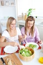 Glowing female friends eating salad in the kitchen Royalty Free Stock Photo