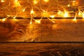 Glowing festive lights on wooden background, top view. Space for text