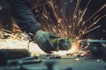 Glowing flow of sparks around an angle grinder while cutting a piece of steel tube pipe on a work surface