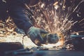 Glowing flow of sparks made by sawing a piece of steel with an angle grinder on a work surface