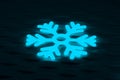 Glowing frozen snowflake on dark wall. Neon effect. Large snowfalls in winter