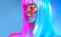 Glowing gold skin. Fashion model woman face in bright neon colourful lights, beautiful sexy woman with white hair and trendy make- Royalty Free Stock Photo