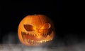 Glowing Halloween jack-o-lantern pumpkin on a black background. Helloween pumpkin with evil face on a wooden table Royalty Free Stock Photo