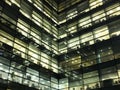 Glowing illuminated windows in a large modern geometric city office building at night showing work spaces