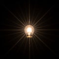 A glowing incandescent light bulb is centered against a dark background Royalty Free Stock Photo