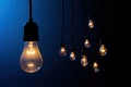 Glowing incandescent light bulbs hanging in the dark with a blue background Royalty Free Stock Photo