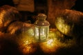 Glowing lantern on hay bale and golden pumpkins in dark, mystical atmospheric image. Modern festive halloween street decor, candle